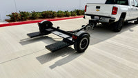 Premier tow dolly connected to pickup truck, diamond plate swivel pan and steel mesh ramps visible