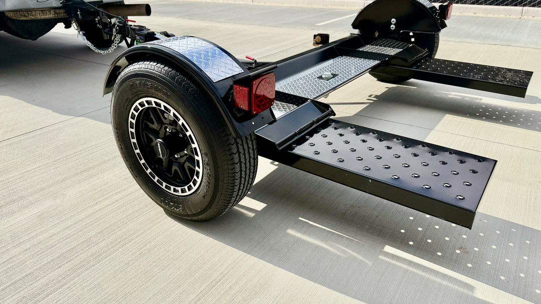 Close-up of tow dolly steel mesh loading ramp, LED tail light, and Raceline alloy wheel