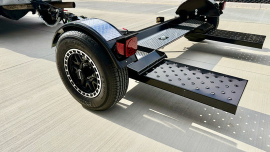 Close-up of tow dolly steel mesh loading ramp, LED tail light, and Raceline alloy wheel